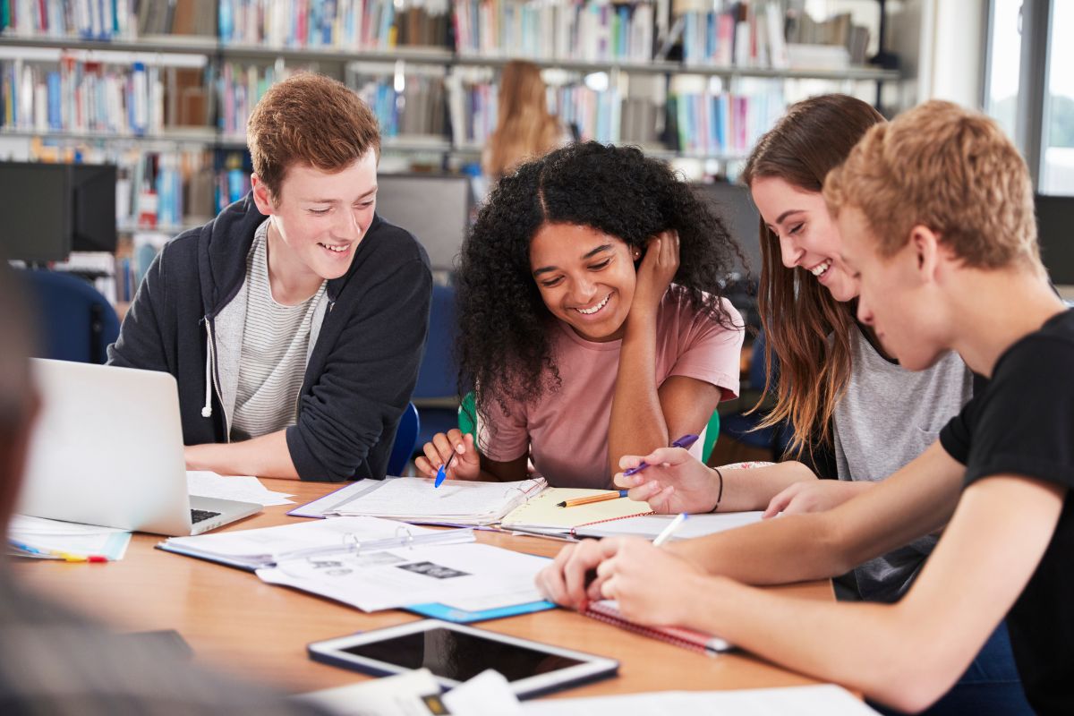 Canadian-Accounting-Students-Studying Diverse group of students collaborating on accounting coursework in a Canadian school library with notebooks and digital devices